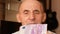 Close-up of 500 euro banknote in the hands of a Caucasian pensioner. Finance and seniors theme. Portrait of an elderly man looking