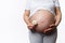 Close-up abdomen of a pregnant woman, expectant mother holding daisy flower near her belly. Obstetrics and gynecology