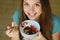 Close up from above of beautiful young woman smiling and eating skyr with cereal muesli fruit and seeds at home, focus on the