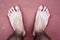 A close up from above of caucasian young man`s bare feet standing on red ground. Concept of feet care