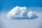 A close up abstract photograph of a single textured white puffy cloud against a blue sky