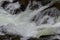 Close-up abstract texture above view of river torrent and clear fresh cold water flowing through mountain rocks in valley with