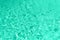 Close up abstract water texture. Swimming pool water in mint color background. Trendy green and turquoise color. Copy space, top