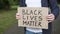 Close-up of the activist`s hands holds a cardboard with the words black lives matter.