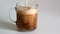 Close-up of adding milk to a glass mug with fresh fragrant black coffee with foam crema