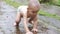 Close up of adorable baby crawling on the pavement under the rain.