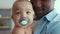 Close up of adorable black baby with nipper on african american father's hands , looking at camera, slow motion