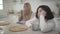 Close-up of adult brunette Caucasian woman siting with coffee cup at the table. Her blond female friend drinking hot