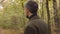 Close-up of an adult Caucasian man standing in the forest and turning around. Guy in casual clothes enjoying calm quiet