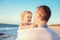 Close up adult father holding his happy blondy child girl daughter on the hands and having fun walking on the beach. Family vacati