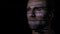 Close up of an adult male IT programmer working in a dark office room while the sequential code is reflected on his face -