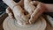 Close-up of adult man`s hands helping kid during craftswork on throwing wheel