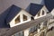 Close-up aerial view of building attic rooms exterior on metal shingle roof, stucco walls and plastic windows