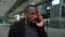 Close-up of an African-American arguing on a smartphone in a modern city. An angry businessman is on the phone outside