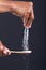 Close-up of african american man hand sprinkling seasoning on wooden spoon against black background