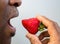 Close up of an African American man holding a strawberry to his mouth