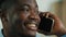 Close up african american man talking phone indoors ethnic smiling male 30s businessman speak with mobile smartphone