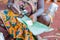 Close up of african woman hands filling plantain leaves with manioc to make traditonal cameroonian baton de manioc in village