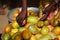 Close Up Of An African Woman`s Hands Fetching Ripe Mangoes From A Basket