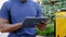 Close up afro-american man courier food delivery sitting on bench uses tablet