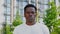 Close up afro-american man looks camera on background modern building in summer