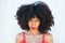 Close-up of Afro-American woman with tousled hair, looking intrigued and strange. The beautiful woman is wearing a red top and red