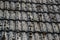 Close up of aged roofing tiles on old house in village. A lot of moss on tiled roof of hovel. Countryside scene