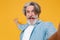 Close up of amazed elderly gray-haired mustache bearded man in casual blue shirt posing isolated on yellow background