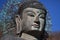 Close-up ancient metal carving of sitting peace buddha in front of tree mountain