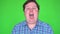 Close-up of angry fat man screaming against green background.