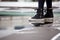 close up Ankle Sneakers of woman standing on water puddle on street in city