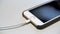 Close up of the apple iphone with the charging cable lying on the white table. Media. Process of charging of a modern