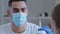 Close-up arabic spaniard man in medical mask sits in clinic hospital preparing for vaccination injection looks at