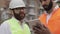 Close up of architect hands using tablet near construction site. The builder and architect man are discussing the