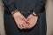 Close-up. Arrested woman handcuffed hands at the back isolated on gray background