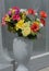 Close up of artificial flowers in vase by grave stone