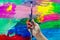 Close up of an artist or painter hands holding dirty paint brushes on colorful picture