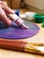 Close-up of the artist\'s hand squeezed from a tube paint on an easel. Brushes, paints, an easel on the table