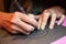 Close up of artists hands while making a custom designed paper cutting art work using a scalpel.  Papercraft by hand