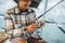 close up of Asian angler checking reel while holding rod