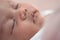 Close up asian baby infant face closing eyes sleeping on bed.
