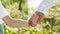 Close up of Asian father & son holding hand & walking in garden in morning