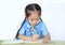 Close-up Asian little girl in school uniform writing on notebook at desk isolated on white background. Schoolgirl and Education