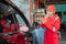 Close up of Asian man in red uniform welcomes when customers come by car to be repaired