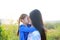Close up Asian mother and daughters kissing in the meadow field at morning