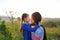 Close up Asian mother and daughters kissing in the meadow field at morning sunrise
