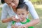 Close-up Asian mother wipe baby mouth by tissue in the garden outdoor