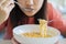 Close up Asian woman eating yummy hot and spicy instant noodle using chopsticks and bowl