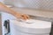 Close up of Asian woman hand flushing toilet with tissue paper to prevent direct contact for COVID-19, virus, bacteria germs and
