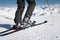 Close-up of the athlete`s skier`s foot in ski boots rises into the skis against the background of the snow-capped